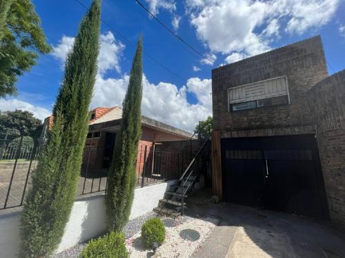 uma casa com duas árvores altas em frente em Habitacion en Carrasco Sur, cerca del aeropuerto y la rambla em Montevidéu