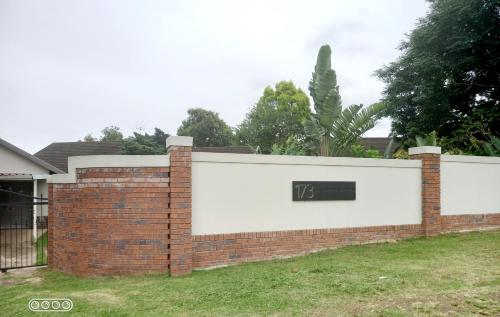 a brick fence with a clock on it at Secret Guest House in Pietermaritzburg