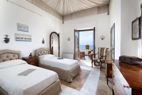 - une chambre avec 2 lits, un bureau et une table dans l'établissement Estate4home - Villa Elsa, à Positano