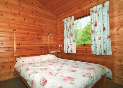 a bedroom with a bed in a log cabin at Spindlewood Lodges in North Wootton