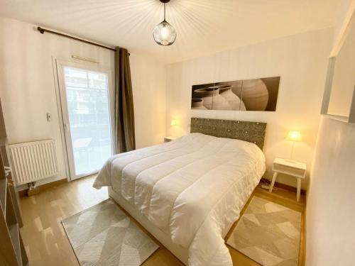 a bedroom with a white bed and a window at CAPTAL beau 2 pièces cœur de ville parking terrasse in La Teste-de-Buch