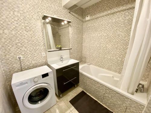 a bathroom with a washing machine and a bath tub at CAPTAL beau 2 pièces cœur de ville parking terrasse in La Teste-de-Buch