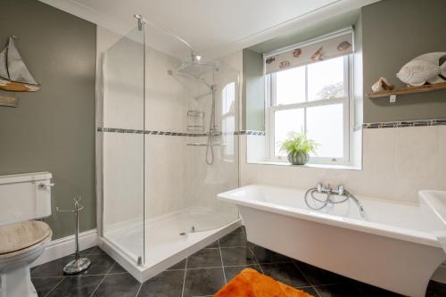 a bathroom with a tub and a shower and a sink at Mae Cottage in Richmond