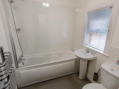 a white bathroom with a tub and a sink at 1 Bed in Bude 78610 in Bude