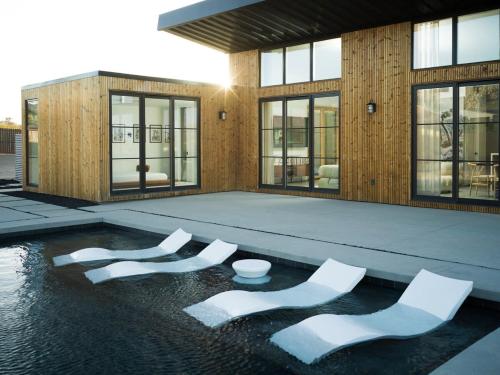 a building with white chairs sitting in the water at The Lunawood - Lux Home Pool and Spa in Joshua Tree