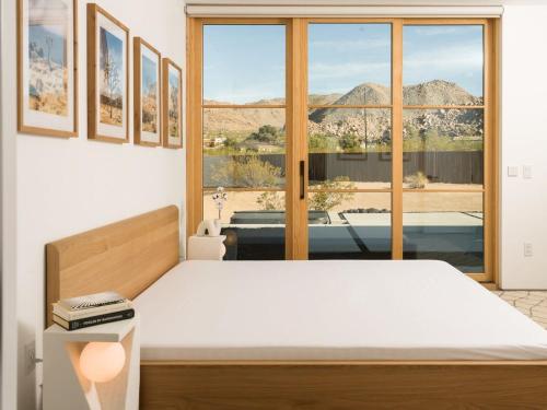a bedroom with a bed and a large window at The Lunawood - Lux Home Pool and Spa in Joshua Tree