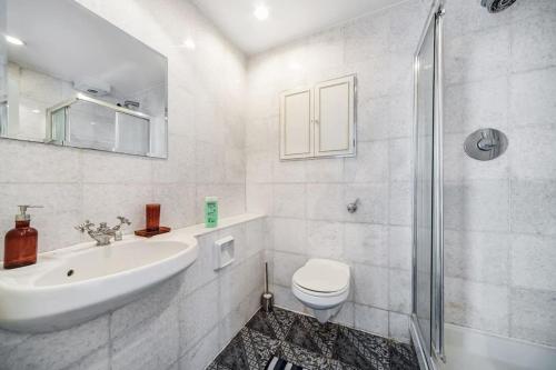 W łazience znajduje się umywalka, toaleta i prysznic. w obiekcie Stunning 4-Bed Apartment w Londynie