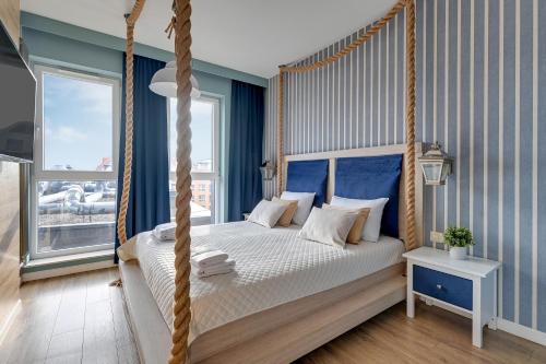 a bedroom with a canopy bed with blue walls at Staywin Prime Apartments Chmielna in Gdańsk