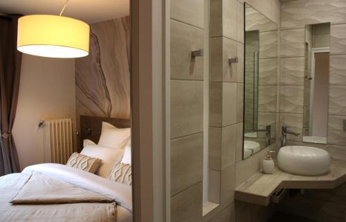 a bedroom with a bed and a sink and a mirror at L'Escale de Beauregard in Coublevie