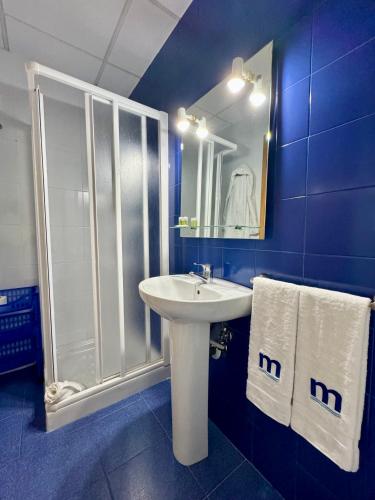 a blue bathroom with a sink and a shower at Residencia Mediterraneo in San Vicente del Raspeig