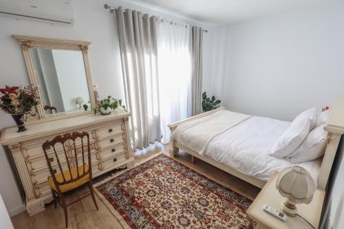 a bedroom with a bed and a mirror and a chair at Sonorus Apartment in Korçë