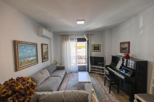 a living room with a couch and a piano at Sonorus Apartment in Korçë