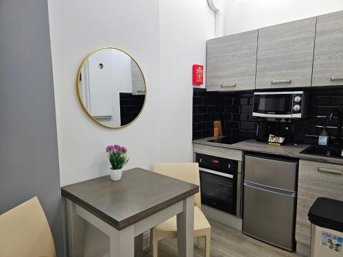 a small kitchen with a table and a mirror at London Stay Apartments in London