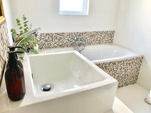 a white sink in a bathroom with a bath tub at Dream On Cottage in Prince Albert