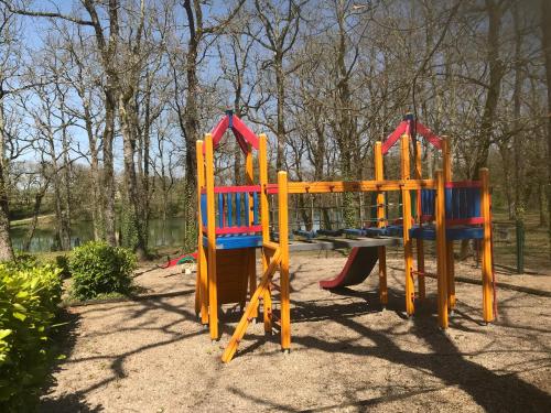 einen Spielplatz mit farbenfroher Ausstattung in einem Park in der Unterkunft Appartement 4 pers1 chb Résidence du Lac vue sur les bois in Monflanquin