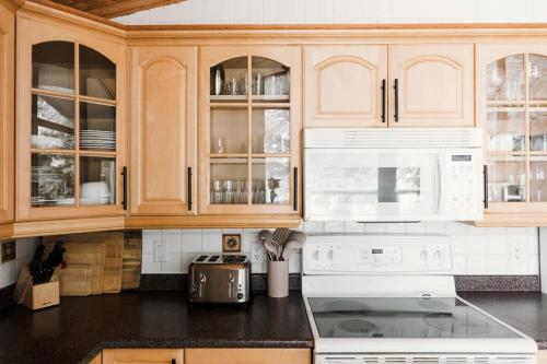 a kitchen with white appliances and wooden cabinets at Alpine Lake House - Waterfront on Lake Muskoka in Port Carling