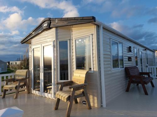 a tiny house with two chairs on a deck at Alphi 4 in Bude