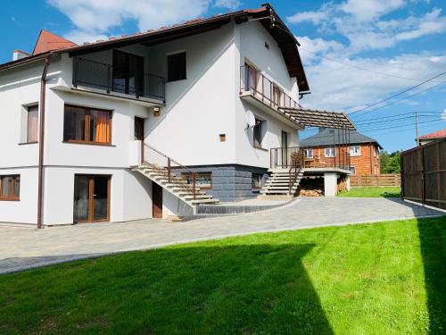 a white house with stairs and green grass at Dom Janosik in Kacwin