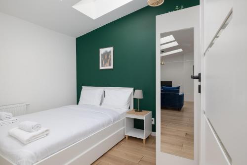 a bedroom with a white bed and a green wall at Plac Grunwaldzki Happy Apartment in Szczecin