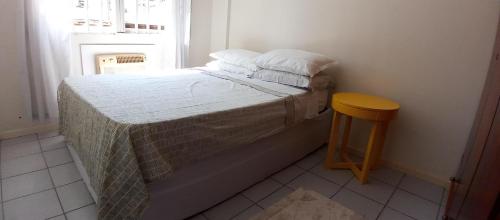 een kleine slaapkamer met een bed en een kruk bij Amplo apartamento para aluguel diário numa das melhores praias de SC. in Meia Praia