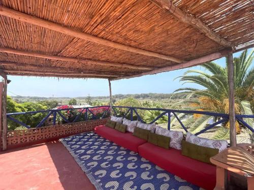 a patio with a red couch under a wooden roof at KHAMBEACH in Azemmour