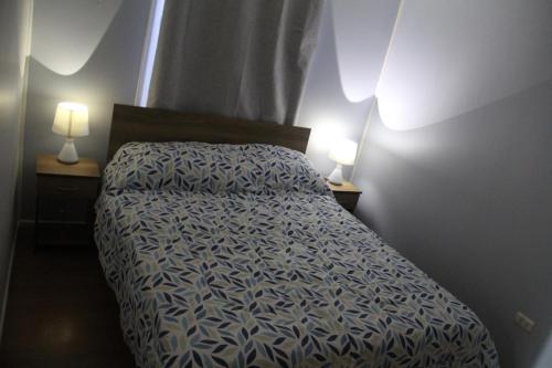 Cama en habitación pequeña con 2 lámparas en Catemahouse, en Coyhaique