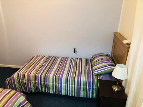 1 dormitorio con 1 cama con colcha a rayas en Catemahouse, en Coyhaique