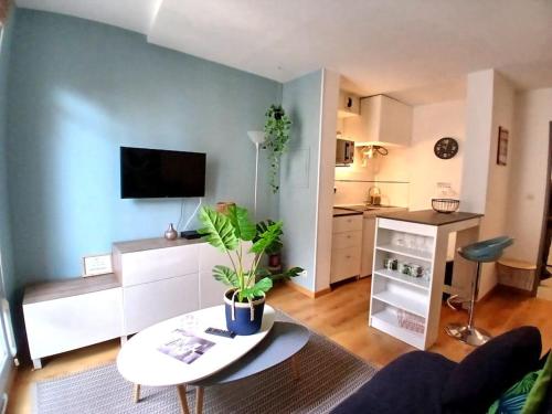 ein Wohnzimmer mit einem Sofa und einem Tisch sowie eine Küche in der Unterkunft Studio cosy au cœur de Nîmes. in Nîmes