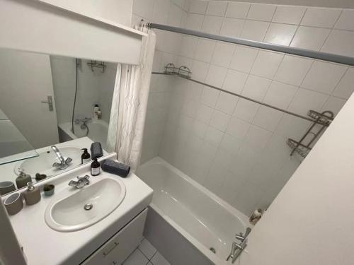 une salle de bain blanche avec un lavabo et une douche dans l'établissement Bel Appartement à Bécon, à Asnières-sur-Seine