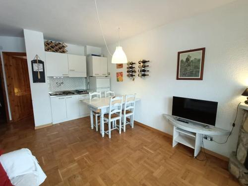 uma cozinha e sala de jantar com uma mesa e uma televisão em [Prato Nevoso] Appartamento fronte conca em Prato Nevoso