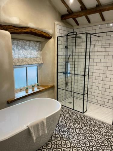 La salle de bains est pourvue d'une baignoire et d'une douche en verre. dans l'établissement The Hatch Inn, à Taunton