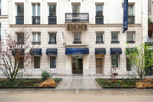 un grand bâtiment blanc avec des auvents bleus. dans l'établissement Nets Inn Apartments - Saint Lazare, à Paris