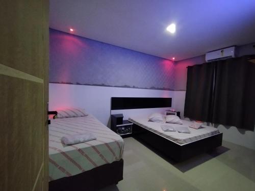 2 camas en una habitación con luces moradas en Hotel motel Raiar do Sol santo Amaro, en São Paulo