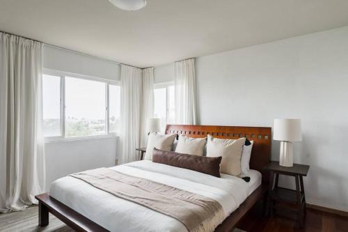 a white bedroom with a large bed and windows at Solana Beach Home 4 blocks from the Ocean in Solana Beach