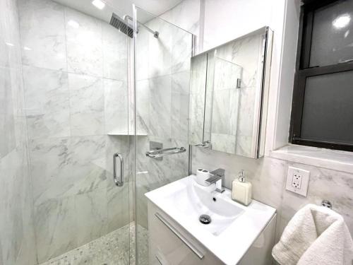 a white bathroom with a sink and a shower at 62-2B Renovated 1BR in Prime Upper East Side in New York