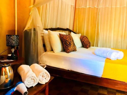 Atha Safari Resort & Riverside Camping في اوداوالاوي: غرفة نوم عليها سرير وفوط