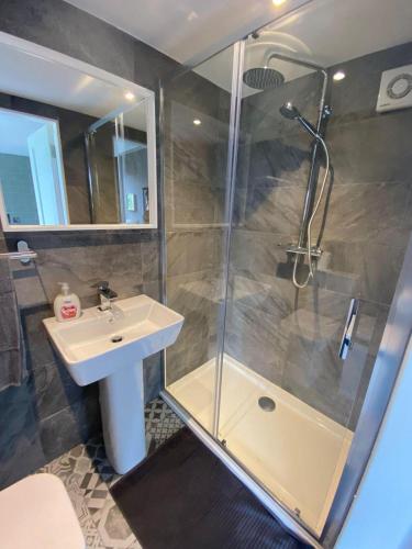 y baño con ducha acristalada y lavamanos. en Stunning Ashbourne Log Cabin No4, en Ashbourne