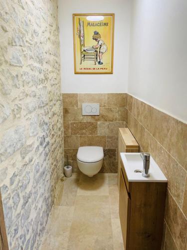 a bathroom with a toilet and a poster on the wall at Grange avec vue, proche de Sarlat, calme et dépaysement au coeur du Lot in Beaumat