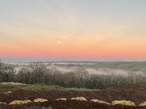 a sunrise over a foggy field with the moon in the sky at Grange avec vue, proche de Sarlat, calme et dépaysement au coeur du Lot in Beaumat