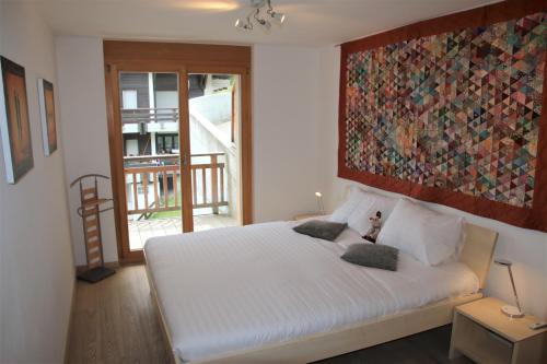 a bedroom with a white bed with a large painting on the wall at Ski Paradise SP 008 - MOUNTAIN & LUXE apartment 4 pers in Veysonnaz