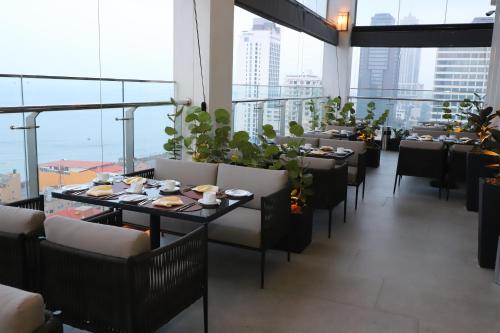 uma sala de jantar com mesas e cadeiras e janelas grandes em Sofia Colombo City Hotel em Colombo