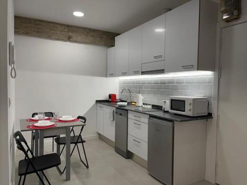 uma cozinha com armários brancos, uma mesa e um micro-ondas em Donosti House Hiru con Parking ESS03051 em San Sebastián