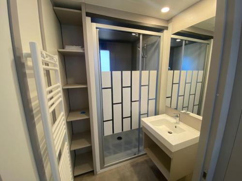 une salle de bain blanche avec un lavabo et une douche dans l'établissement Cottage avec piscine à 300m de la plage, à Jullouville