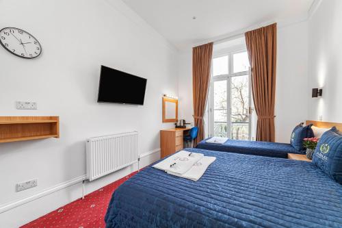 pokój hotelowy z dwoma łóżkami i telewizorem w obiekcie Jubilee Hotel Victoria w Londynie