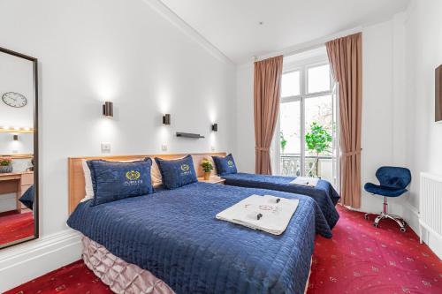um quarto com 2 camas com lençóis azuis e uma janela em Jubilee Hotel Victoria em Londres