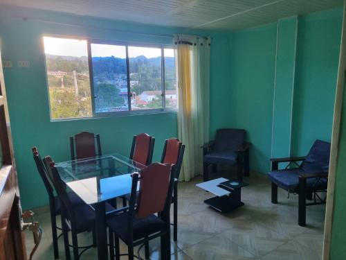 ein Wartezimmer mit einem Tisch, Stühlen und einem Fenster in der Unterkunft Hospedaje San Alberto 202-Ráquira in Ráquira