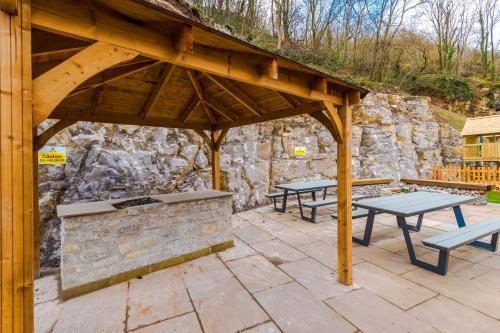 a patio with two picnic tables and a stone wall at Rock Mill - Deluxe Studio Apartments in Stoney Middleton
