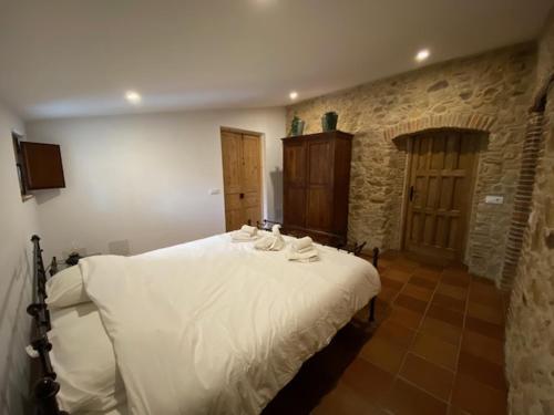 a white bed in a room with a stone wall at Can Massanet in Llagostera