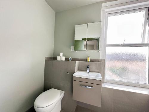 a bathroom with a toilet and a sink and a window at Lovely 2 bedroom flat in Shepherd's Bush with indoor fire place in London