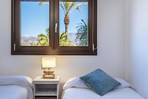 una camera con due letti e una finestra con una palma di Apartamento Dos Mares a Motril